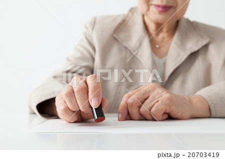 シニア女性　書類に印鑑を押す 20703419