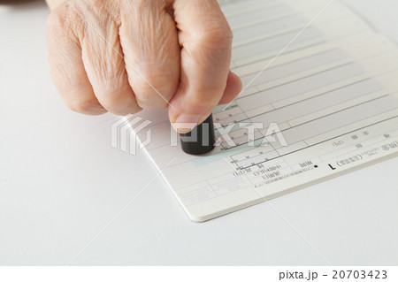 シニア女性　預金通帳に印鑑を押す 20703423