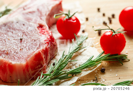 Pieces of crude meat with rosemary and tomatoes. 20705246
