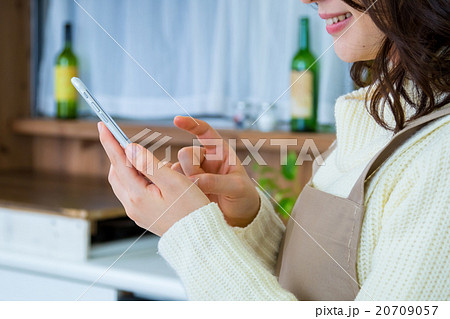 台所でスマホを操作する女性の手元　白い　台所　キッチン　調理場　レシピ検索　メニュー検索 20709057
