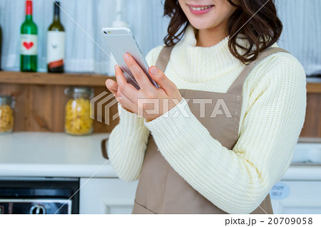 台所でスマホを操作する女性の手元　白い　台所　キッチン　調理場　レシピ検索　メニュー検索 20709058