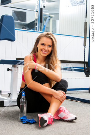 Fit woman sitting on the floor at gym Fit woman sitting on the floor at gym 20721668