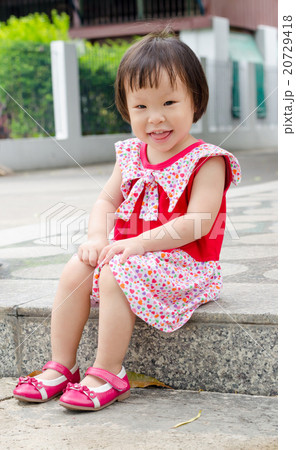 Little Asian girl sitting and smiling outdoor 20729418