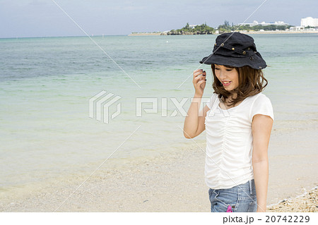沖縄県恩納村の海辺に立って微笑む女性 20742229