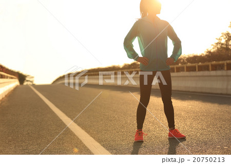 woman runner standing with her hands on hips   20750213