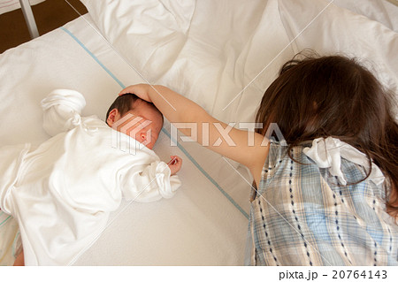 赤ちゃんの頭を撫でる子供の写真素材