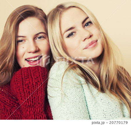 Two young girlfriends in winter sweaters indoors Two young girlfriends in winter sweaters indoors 20770179