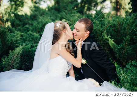 Bride sit together with groom on green grass park  20771627