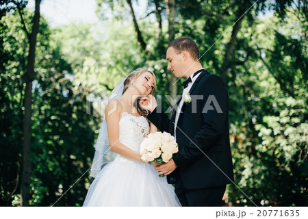 Bride and groom outdoors on a wedding day in park 20771635