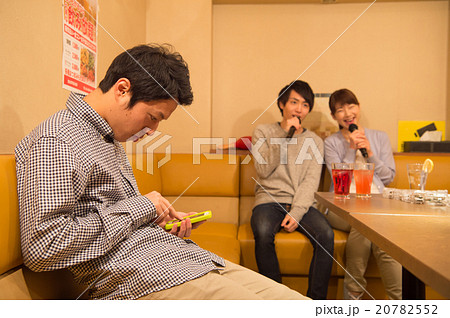 カラオケを楽しむ男女とスマホを見る男性 20782552