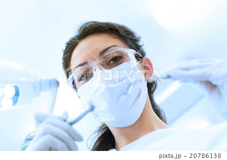 Dentist in mask holding angled mirror and drill 20786138