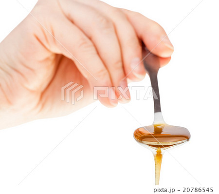 hand holds metal spoon with clear honey hand holds metal spoon with clear honey 20786545