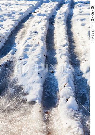frozen car tracks on snowy country road 20786806