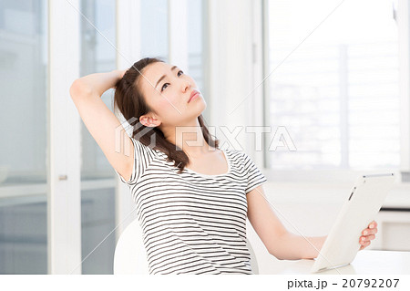 部屋でタブレットを見る女性 考える 部屋でタブレットを見る女性 考える 20792207