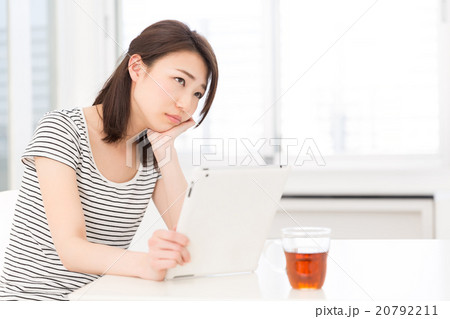 部屋でタブレットを見る女性　考える 20792211