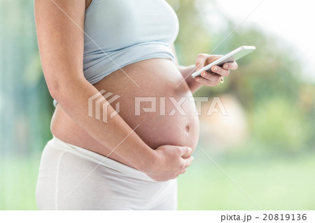Pregnant woman touching her belly and texting Pregnant woman touching her belly and texting 20819136