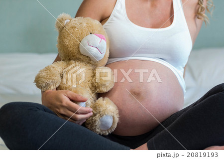 Pregnant woman sitting with a teddy bear Pregnant woman sitting with a teddy bear 20819193