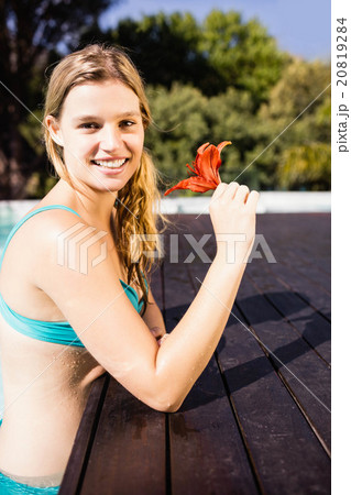 Smiling blonde holding red flower 20819284