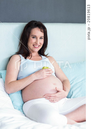 Pregnant woman holding an apple on her belly Pregnant woman holding an apple on her belly 20819613