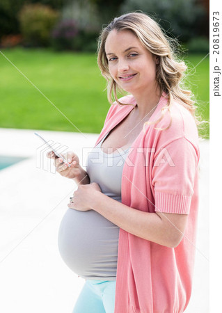 Pregnant woman touching her belly and texting Pregnant woman touching her belly and texting 20819673