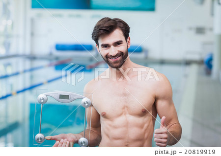 Fit man holding a weighting scale with thumbs up Fit man holding a weighting scale with thumbs up 20819919