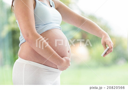 Pregnant woman taking a picture of her belly 20820566