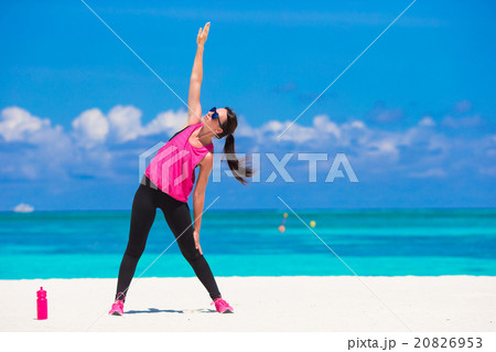 Fit young woman doing exercises on tropical white 20826953