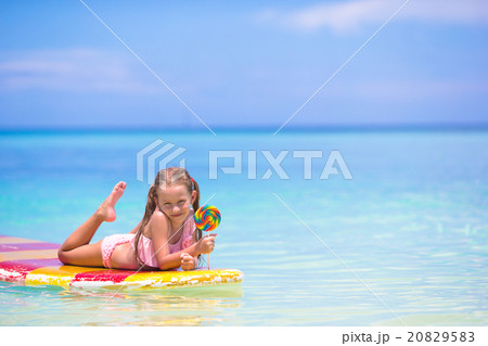 Little girl with lollipop have fun on surfboard in Little girl with lollipop have fun on surfboard in 20829583