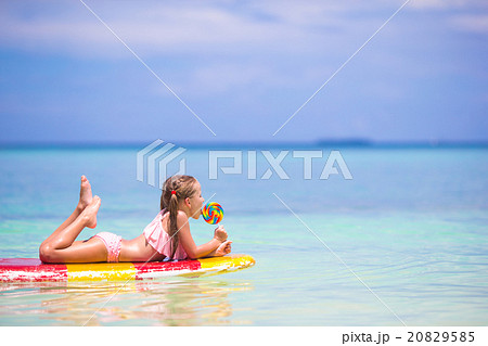 Little girl with lollipop have fun on surfboard in Little girl with lollipop have fun on surfboard in 20829585
