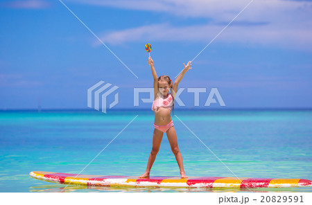 Little girl with lollipop have fun on surfboard in Little girl with lollipop have fun on surfboard in 20829591