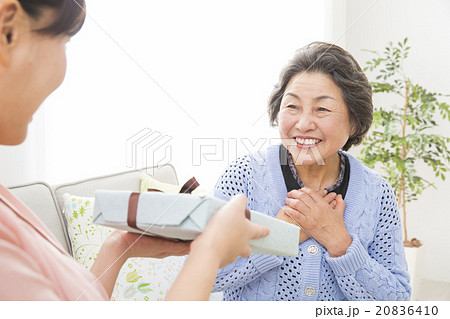 シニア女性にプレゼントを渡す若い女性 シニア女性にプレゼントを渡す若い女性 20836410