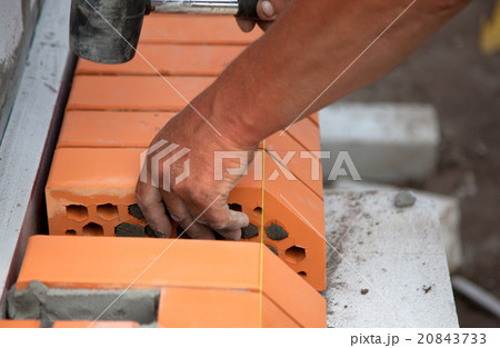 Builder lays bricks in cement mortar 20843733