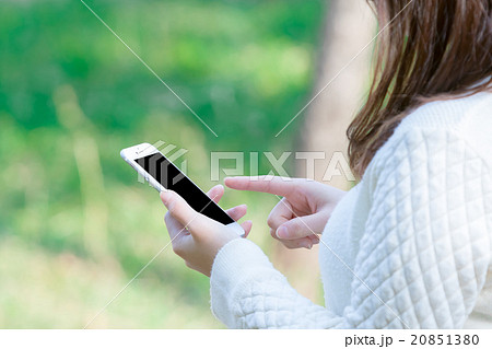 女性　スマホを持った女性の手元　はめ込み合成用写真素材　緑背景　グリーン　企業宣伝用画像素材 20851380