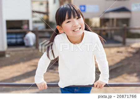 鉄棒で遊ぶ小学生の女の子の写真素材