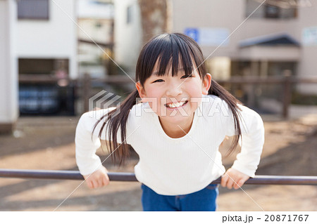 鉄棒で遊ぶ小学生の女の子の写真素材