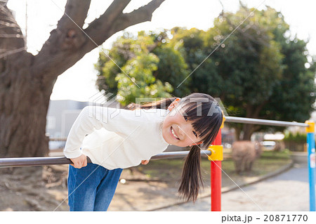 鉄棒で遊ぶ小学生の女の子の写真素材