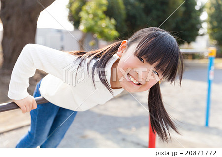 鉄棒で遊ぶ小学生の女の子の写真素材