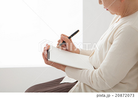 椅子に座ってノートを書くシニア女性　エンディングノート　自分史　手元　アップ 20872073