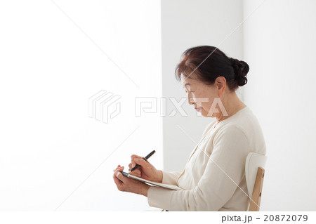 椅子に座ってノートを書くシニア女性　自分史 20872079