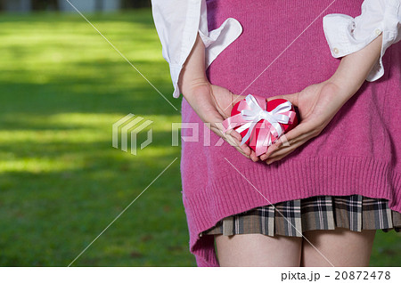 緑を背に後ろ手で可愛いプレゼントを持つ女性　女子高校生　顔なし 20872478
