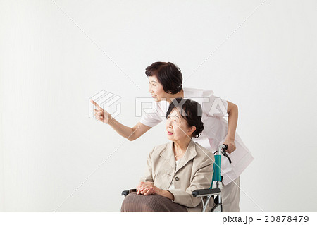 散歩する車椅子の高齢者と介護士　ミドル女性・シニア女性 20878479