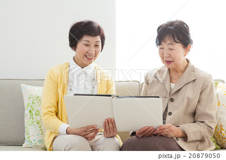 リビングでアルバムを見つめるシニア女性とミドル女性　家族写真　思い出 20879050