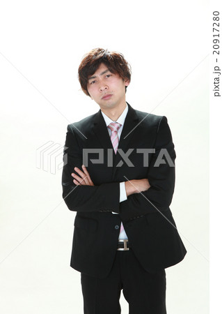 腕組みをして不機嫌そうににらんでいるスーツ姿の代男性ビジネスマンの写真素材 腕組みをして不機嫌そうににらんでいるスーツ姿の代男性ビジネスマンの写真素材