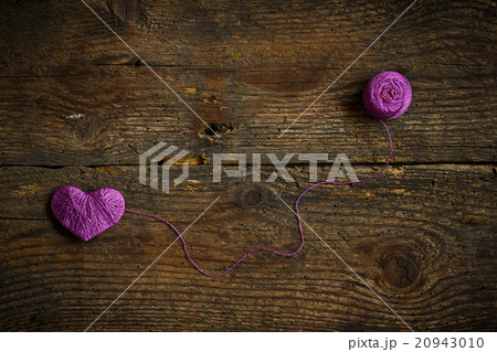 Purple Heart with a ball of thread on on old shabby wooden backg 20943010