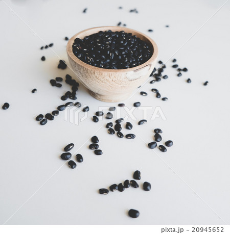 Black beans in a wooden bowl, scattering near 20945652