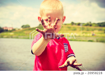 Child playing outdoor showing dirty muddy hands. 20958228