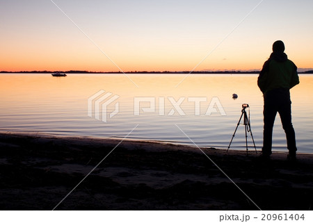 Silhouette of nature photographer at tripod at sea 20961404