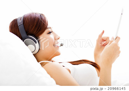 young Woman with headphones and tablet on the bed 20966145