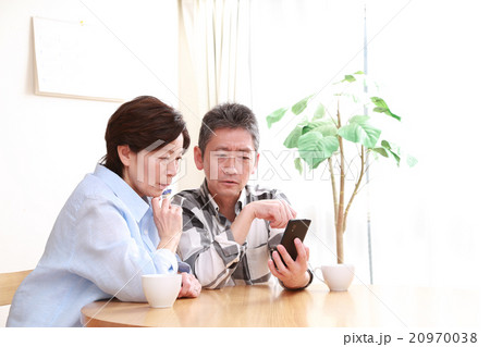 スマホを見て考える50代夫婦 20970038