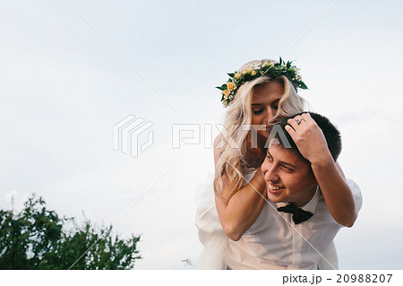 groom carries bride on his back outdoors 20988207